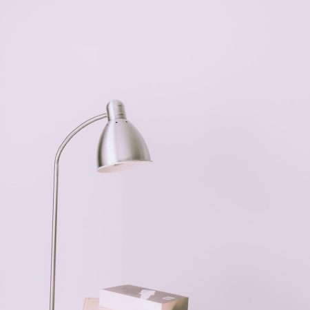 silver desk lamp near pile of books